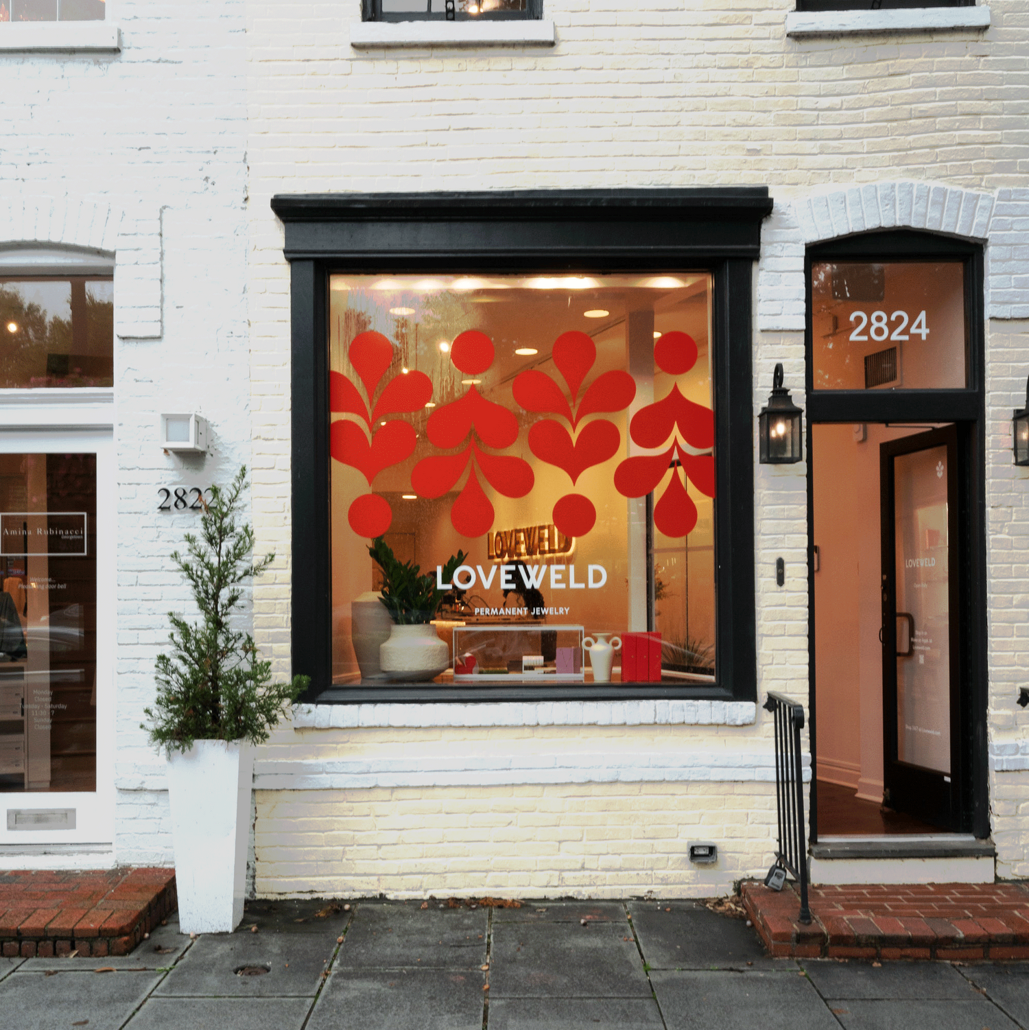 Storefront with decorative window display featuring red floral design and 'LOWEWELD' branding.